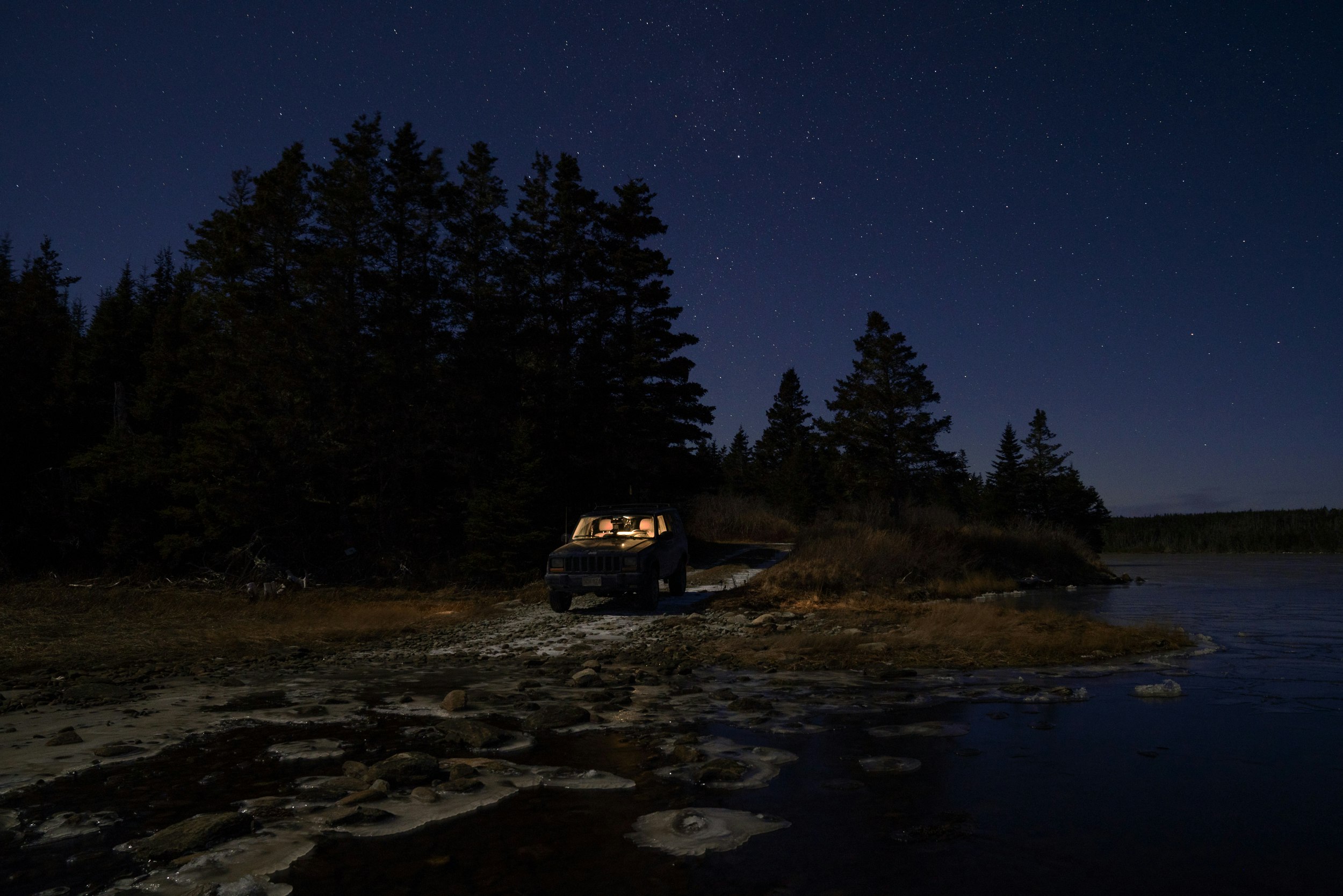 black vehicle parks beside body of water